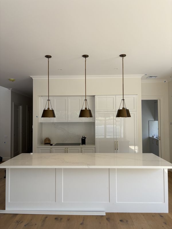 Three brass pendant lights over a white kitchen island