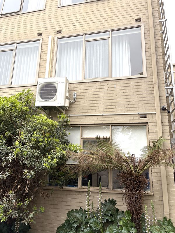 Mitsubishi Electric outdoor unit mounted on the wall of an apartment block