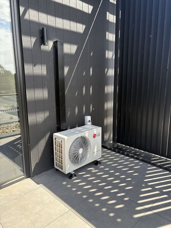 LG split system outdoor unit on a balcony with black capping and an isolator
