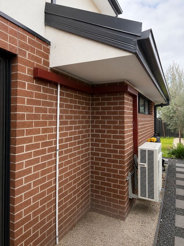 Colorbond capping running along the eaves of a brick house to a split system outdoor unit