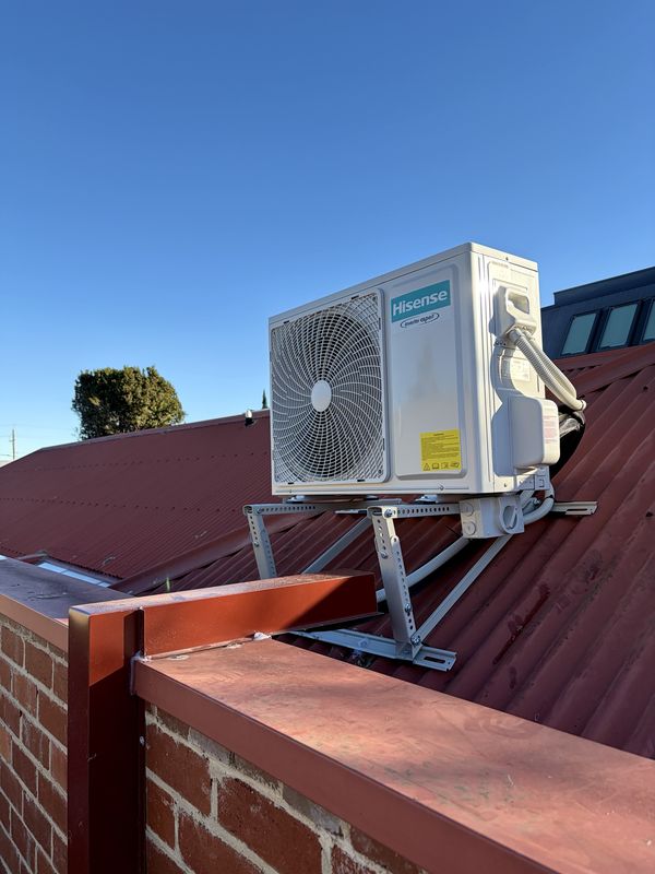Hisense split system outdoor unit on a roof bracket over a corrugated iron roof