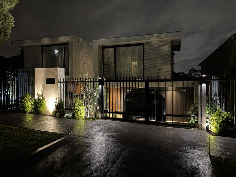 Two townhouses at night with garden uplights, pier lights and gate lighting